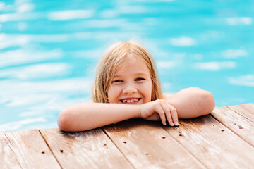 Cute and funny blonde teenage girl on the side of the pool. 