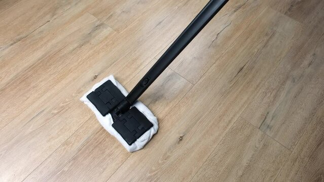 housewife cleans and washes the floor with a steam mop, top view. The concept of environmentally friendly cleaning and disinfection of the house.