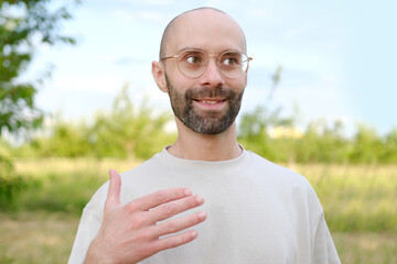 happy satisfied charismatic man in beautiful gold-rimmed glasses, beige t-shirt smiles cheerfully,...