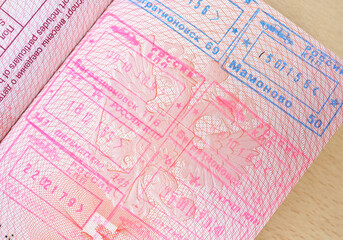 close up part of pages of foreign passport with foreign visas, border stamps, permits to enter countries, concept of traveling around the world, traveler's travel document
