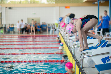 Swimmer girl start from the starting table in the pool - 614897699
