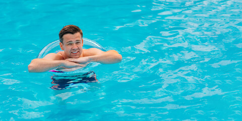 Portrait of a cheerful middle-aged man in the pool with inflatable lifebuoy.