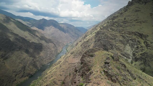 High wide aerial revealing around mountain peak to Hells Canyon and Snake River in Idaho