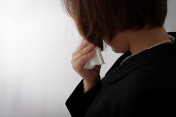 涙を拭く喪服姿の女性