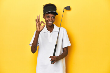 African golfer woman with her golf club, sports concept, cheerful and confident showing ok gesture.