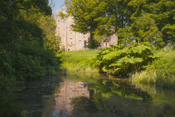 The historic Kellie Castle and gardens reflected in a pond on a sunny summer day in East Neuk, Fife, Scotland, UK.