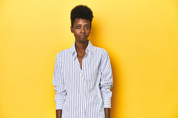 African businesswoman, blue striped shirt, yellow backdrop, sad, serious face, feeling miserable...