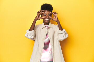 African woman, beige shirt, red striped tee, yellow studio, keeping eyes opened to find a success...