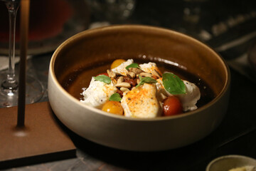  Deliciosa salada com burratas cremosas, suculentos tomates cereja vermelhos e amarelos, crocantes castanhas brasileiras, harmoniosamente decorada com frescas folhas de manjericão.
