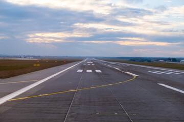 Fototapeta na wymiar At the airport, endless runway extends into the horizon, featuring prominent aircraft markings and well-defined pathways for the safe arrival and departure of planes at sunset