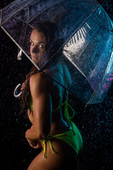 female fitness competitor posing in rain with umbrelle