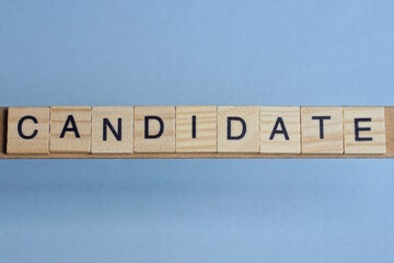 text the word candidate from brown wooden small letters with black font on an gray table