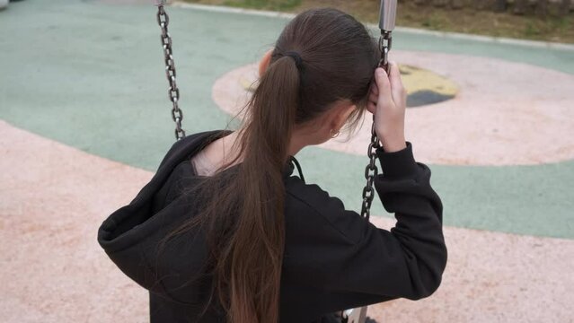 Waiting preteen on park swing. A view of waiting pretten on swing on courtyard in day light.