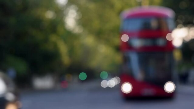 Red double decker bus on a summer green street on a summer day in London. Blurred London public transport. Travel, tourism in England.