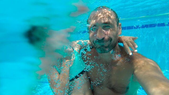 Dad with daughter together dive in pool. A happy dad with smiling child try to diving in the warm home pool in summer. Concept of fun with dad in the pool.