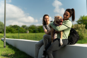 After  jogging, the two girls relax and have fun with their dog, cherishing moments of laughter.
