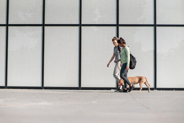 Two girls walk with their dog, relishing the peaceful walk and cherishing the companionship of...