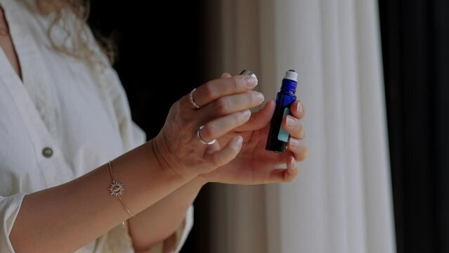 Roller with a fragrance in the hands of a girl, choosing a fragrance for yourself, the concept of creating your own fragrance from natural oils.
