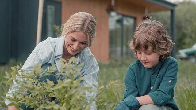 Beautiful mother having positive conversation with her son. Showing gardening process to her kid. Supporting each other. Caring about nature. Family connection. Concept of relationship.