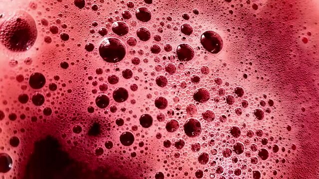 Red bubbles of frothy drink. Background with fermenting liquid. Stock video of alcohol in full hd.
