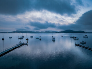 Fototapeta na wymiar Foggy sunrise over the water with boats