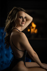 Naklejka premium female posing on a blue couch by a fireplace