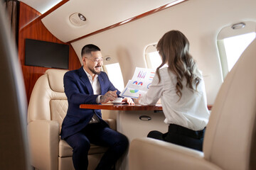 business people at meeting in private plane, asian businessman in suit discusses work with female colleague
