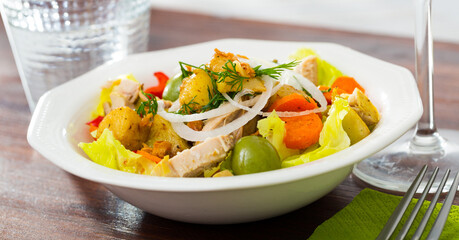 Colorful warm salad with chicken fillets, eggplant, bell pepper, carrots, lettuce and greens with yogurt sauce