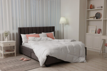 Stylish bedroom interior with comfortable bed, nightstand and lamp