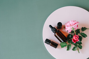 Rose water.Organic cosmetics with rose extract.Rose oil in a glass bottle on a pink podium on a...