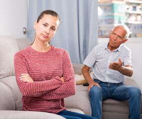Portrait of unhappy woman sitting after quarrel with father at home interior