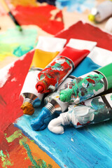 Tubes of colorful oil paints on canvas with abstract painting, closeup