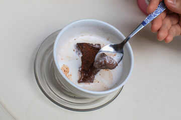 Dark chocolate brownie with milk in white bowl. Good for health. Eating brownie by dipping it into milk is fun. 
