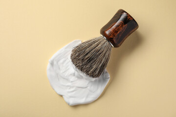 Brush with shaving foam on beige background, top view