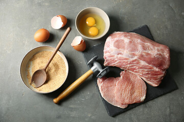 Raw pork chops and ingredients for cooking schnitzel on grey table, flat lay