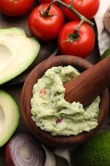 Mortar with delicious guacamole and ingredients on table, flat lay