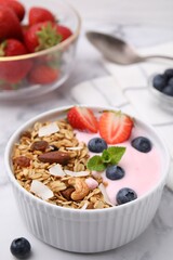 Tasty granola, yogurt and fresh berries in bowl on white table, closeup. Healthy breakfast
