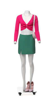 Female mannequin dressed in green skirt and pink top with accessories isolated on white. Stylish outfit