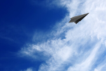 Fototapeta na wymiar White clouds and paper airplane flying in blue sky on sunny day. Space for text