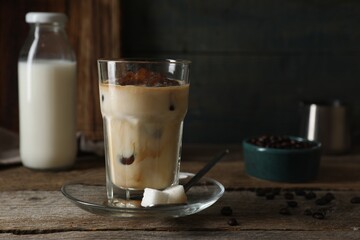 Glass of delicious iced coffee with milk on wooden table. Space for text