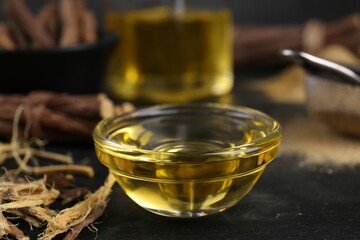 Bowl with licorice essential oil and shavings on black table, closeup