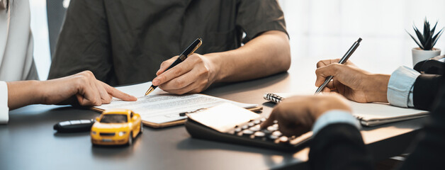 Car dealer calculate interest rate and costs of car loan with calculator, explaining details to...