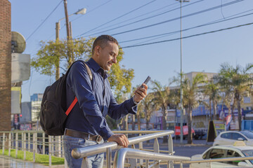 Young latin man looking at his mobile phone with copy space.