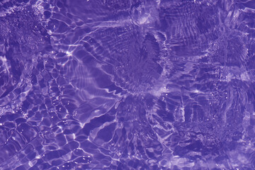 Purple water with ripples on the surface. Defocus blurred transparent pink colored clear calm water surface texture with splashes and bubbles. Water waves with shining pattern texture background.