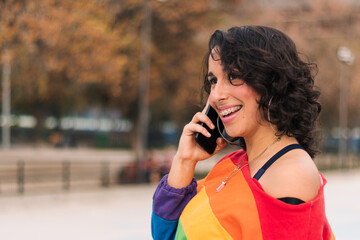 bella chica latina hablando por celular con ropa de arcoíris estilo 80s 90s con maquillaje en la...