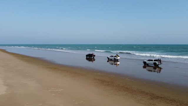 Aerial drone shot over three vehicle driving on the Sapat beach, buji koh in Balochistan during evening time.