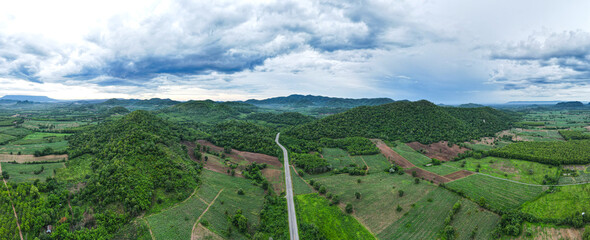 Aerial drone shot Landscape Panorama view, Road cuts through the rice fields. greeneryWhite clouds sky in the background.