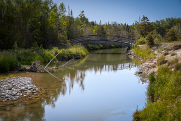 Fototapeta na wymiar The rainbow bridge crosses the river on the River Trail in Inverhuron Provincial Park, Ontario.