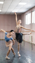 Two Asian ballerinas are dancing in the class. 