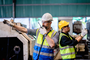 Portrait of Manager mechanical engineer command to staff by using handhold walkie talkie in a repair machine factory.